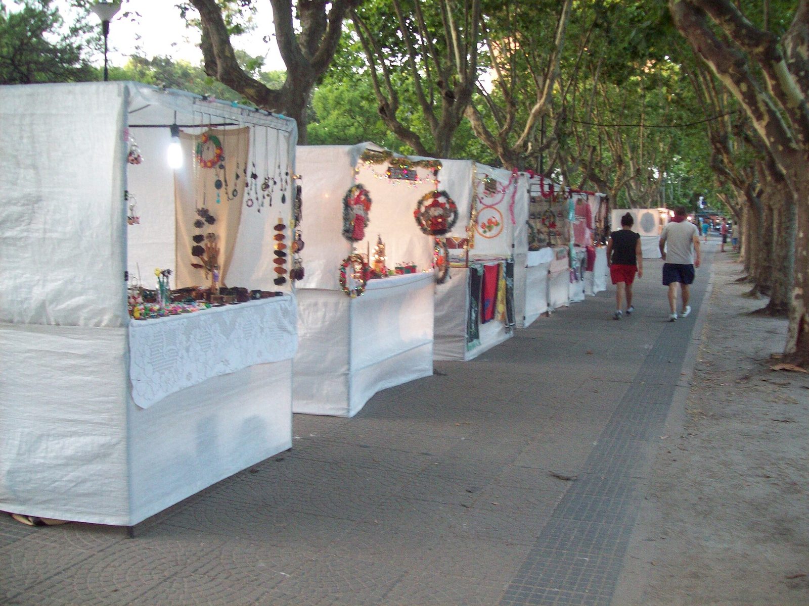 Puestos de la feria de artesanos bajo los árboles de la plaza
